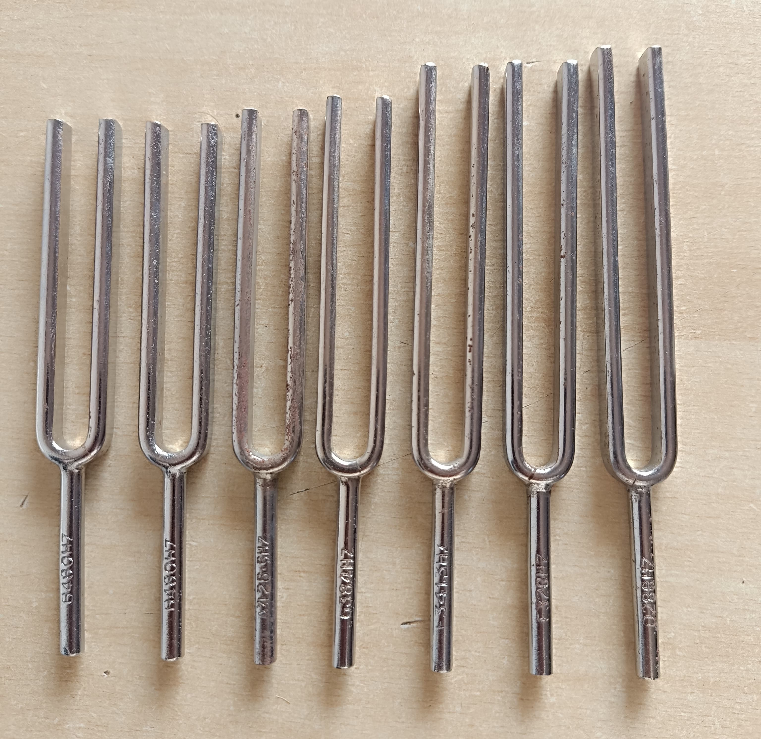 Several metal tuning forks of different sizes laid out side by side.