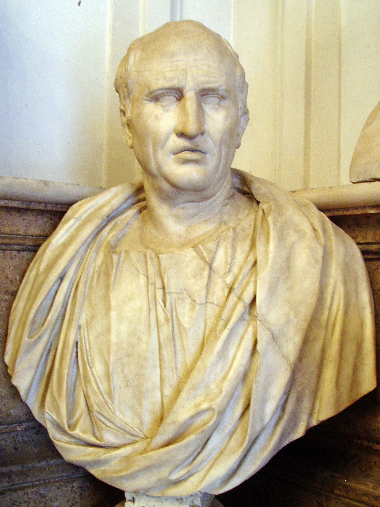A marble bust of an older Roman man with a lined face and receding hair.