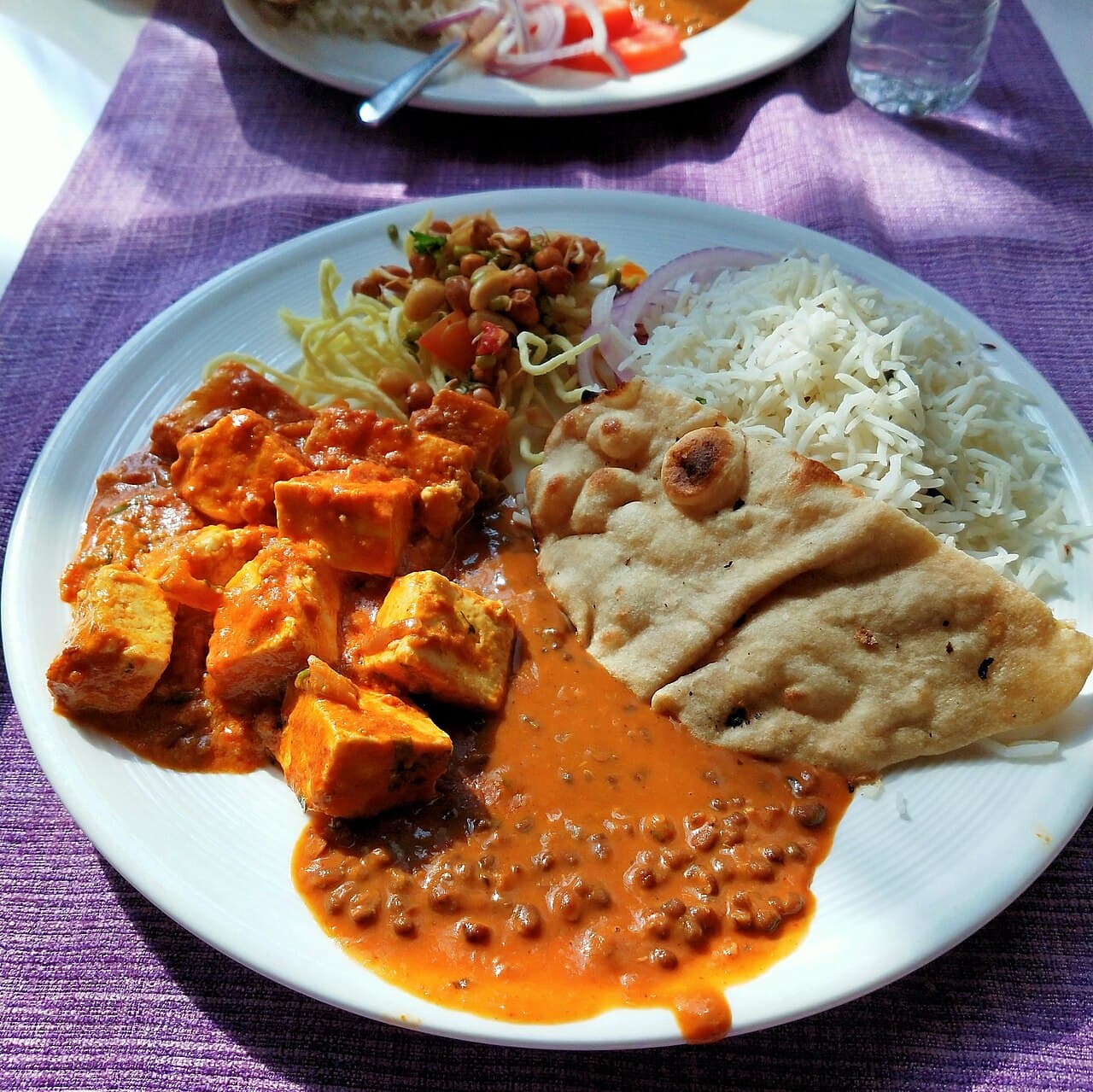 A plate of vegetarian food with vegetables, legumes and rice.