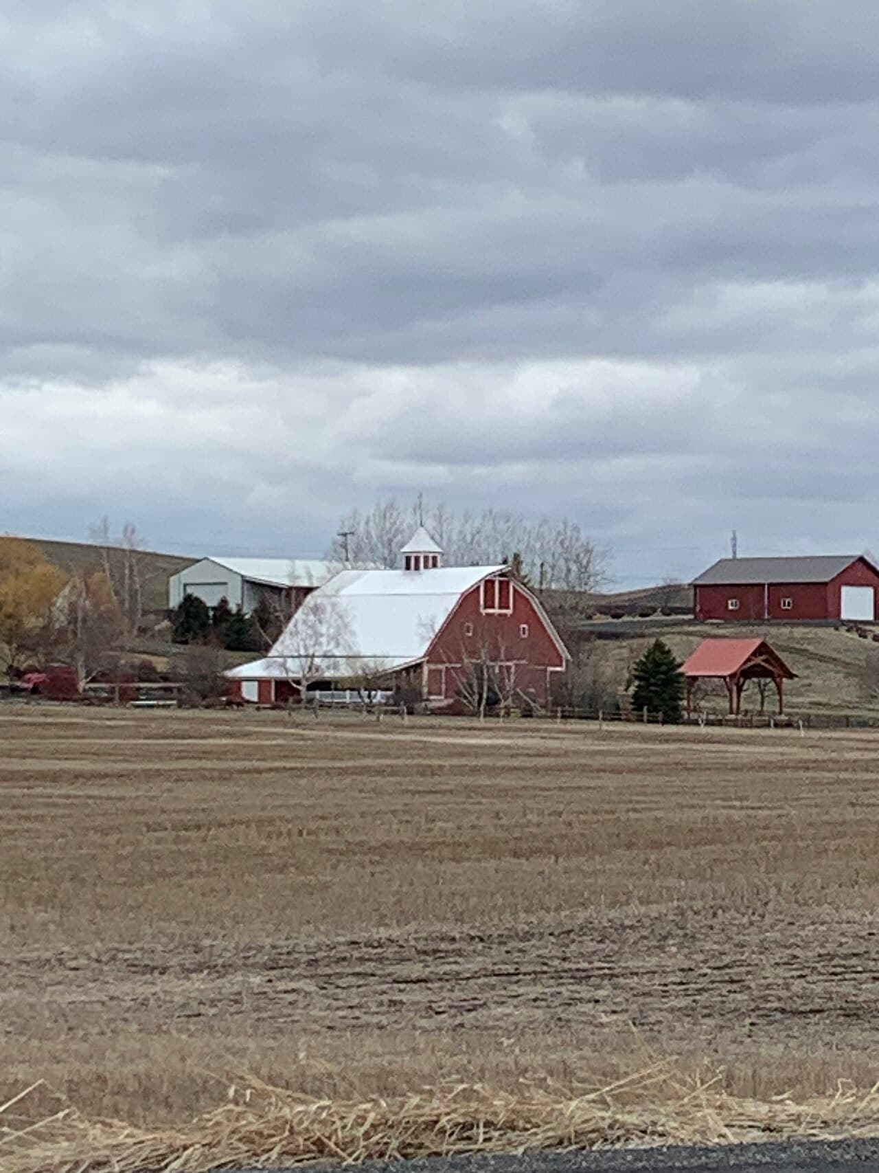 A traditional red barn standing in open farmland, photographed in daylight.