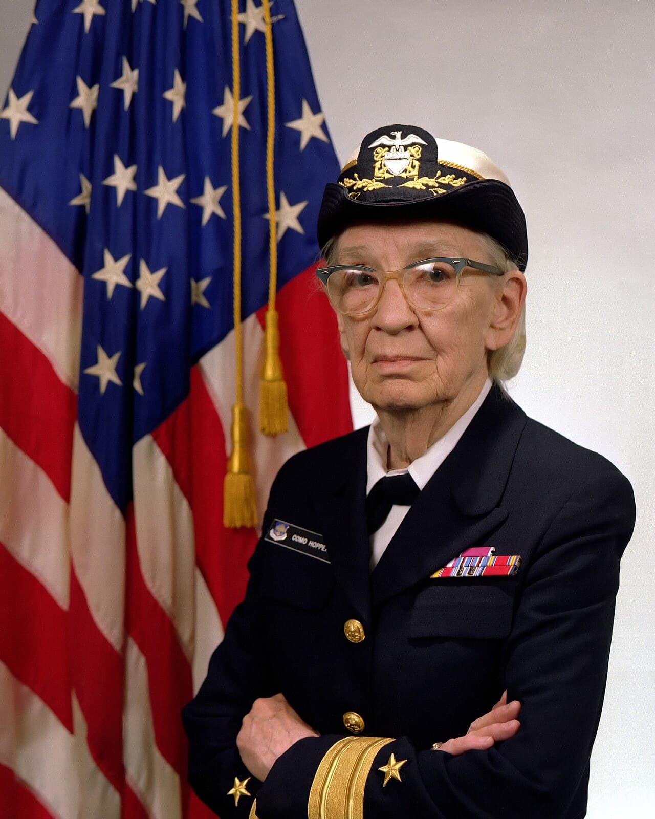 Official Navy portrait of Commodore Grace M. Hopper in uniform, with the American flag in the background.