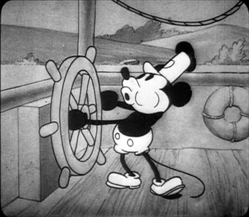 A black-and-white frame from the 1928 cartoon Steamboat Willie showing an early version of Mickey Mouse at the wheel of a steamboat.