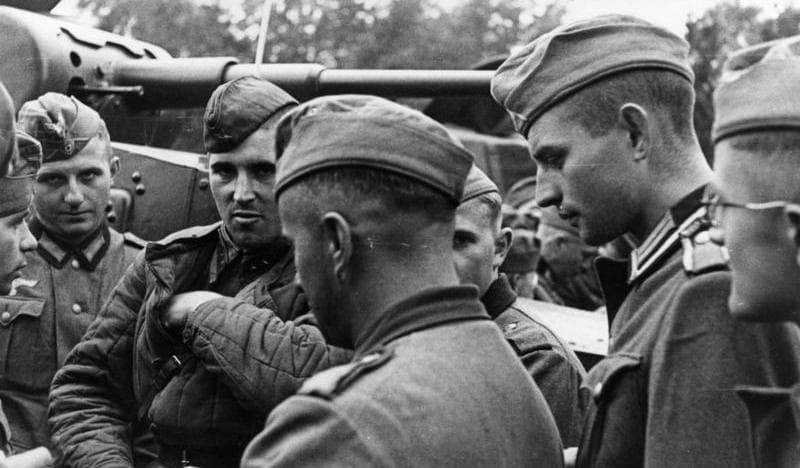 Black-and-white photo of German and Soviet soldiers standing together and talking after jointly invading Poland in 1939.