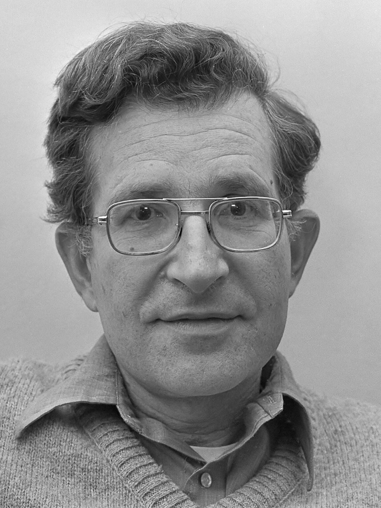 Black-and-white photograph of linguist Noam Chomsky in 1977, wearing glasses and a sweater.