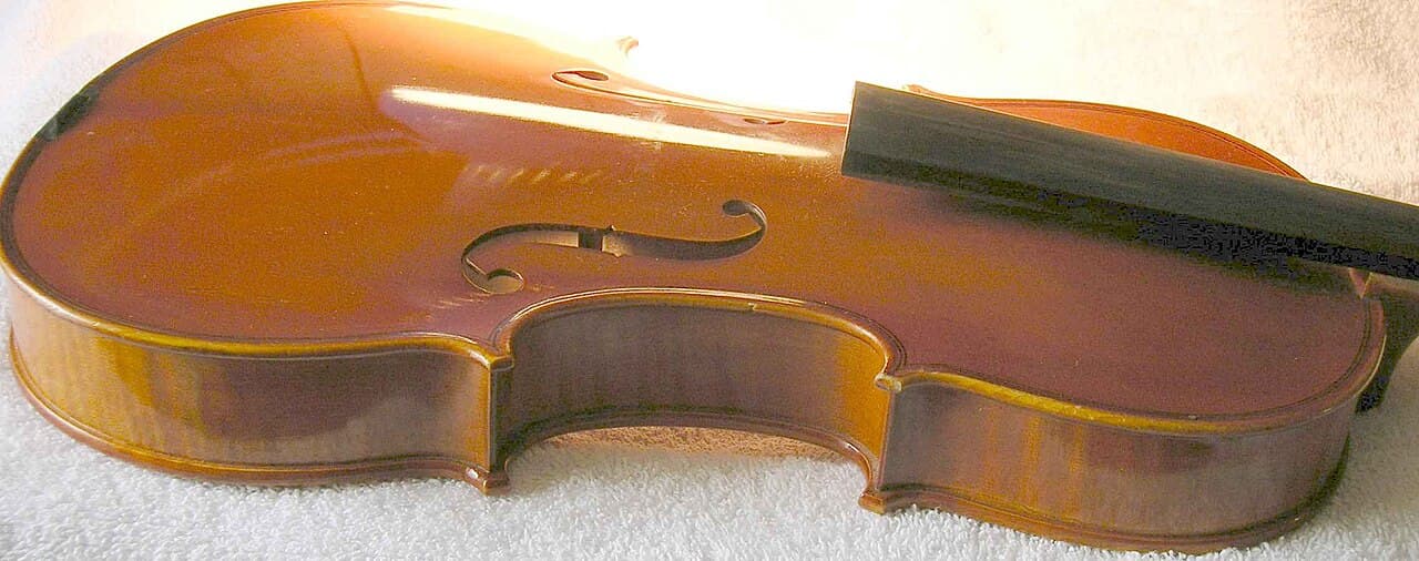 Close-up of a violin's f-shaped sound hole with a small wooden post visible standing upright inside the body.