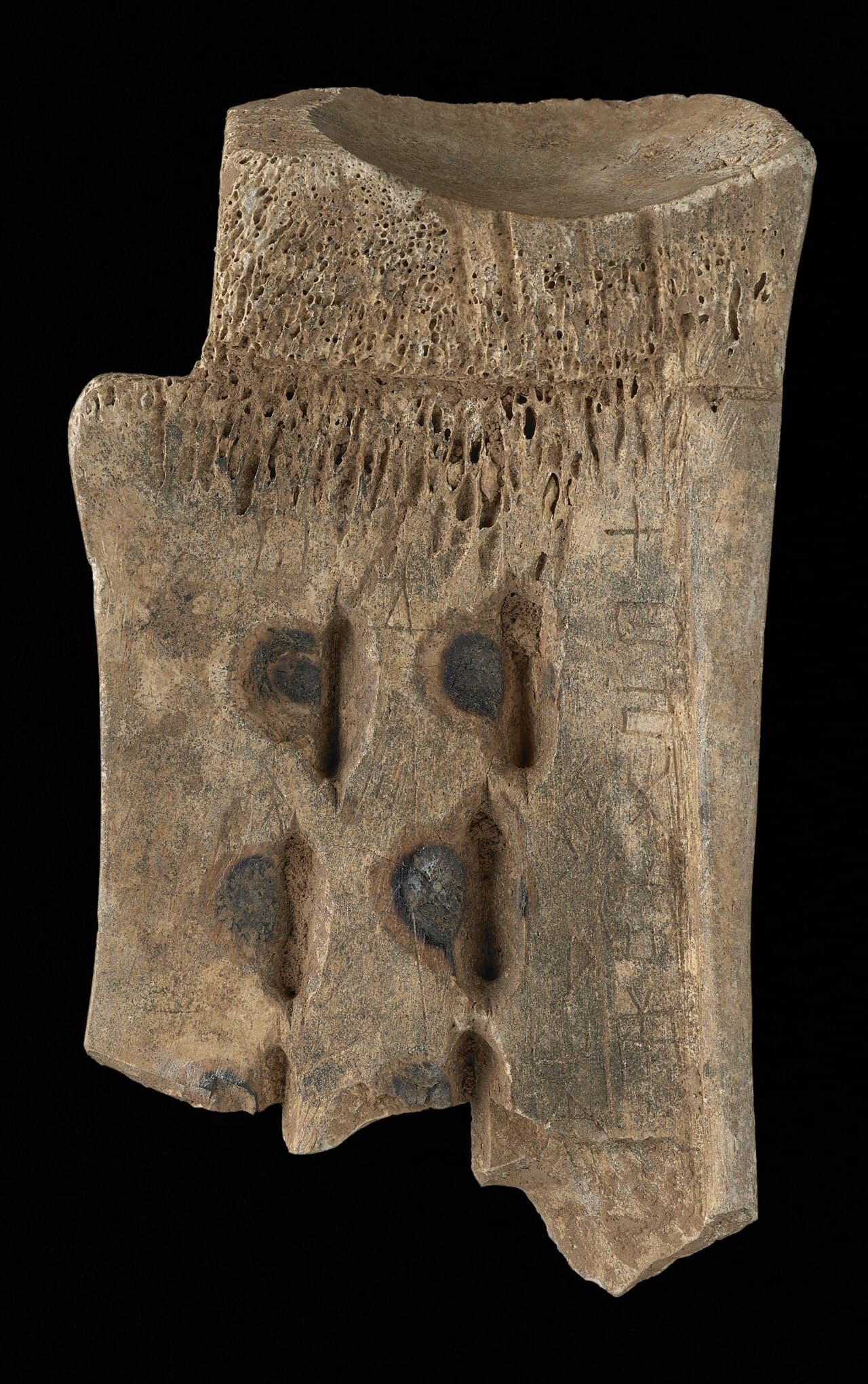 An ancient, cracked oracle bone covered with small carved Chinese characters.