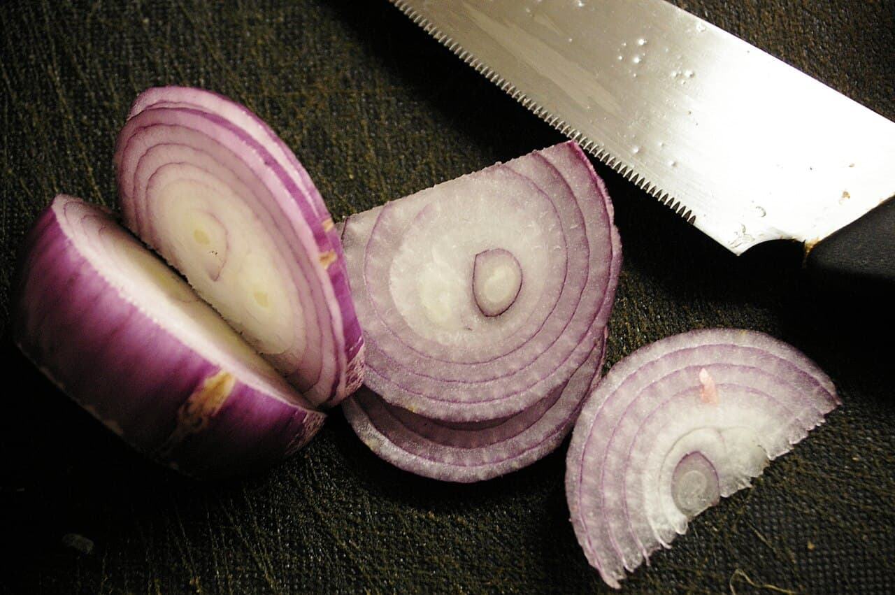An onion being chopped on a cutting board