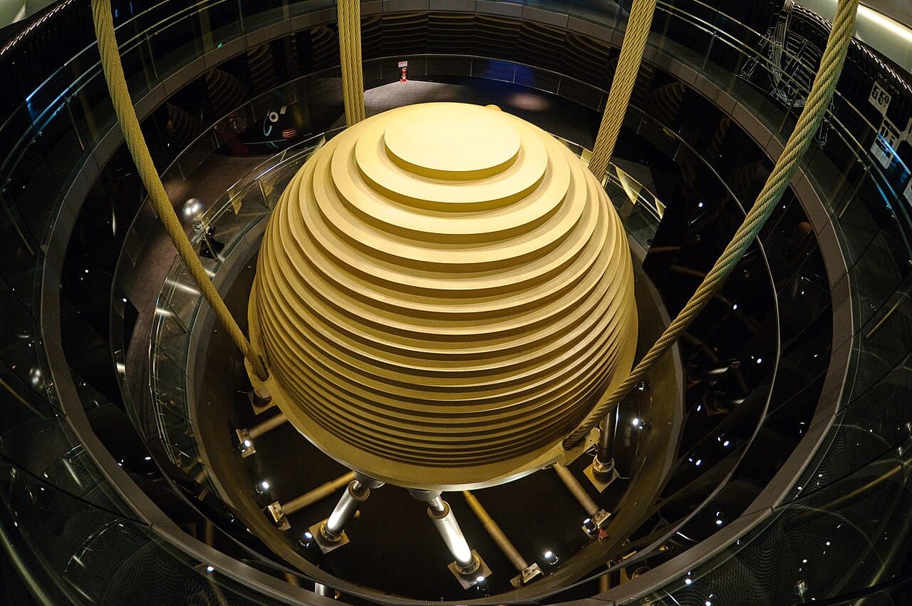 A large golden steel sphere suspended by thick cables inside the upper floors of the Taipei 101 skyscraper, visible to visitors behind glass.