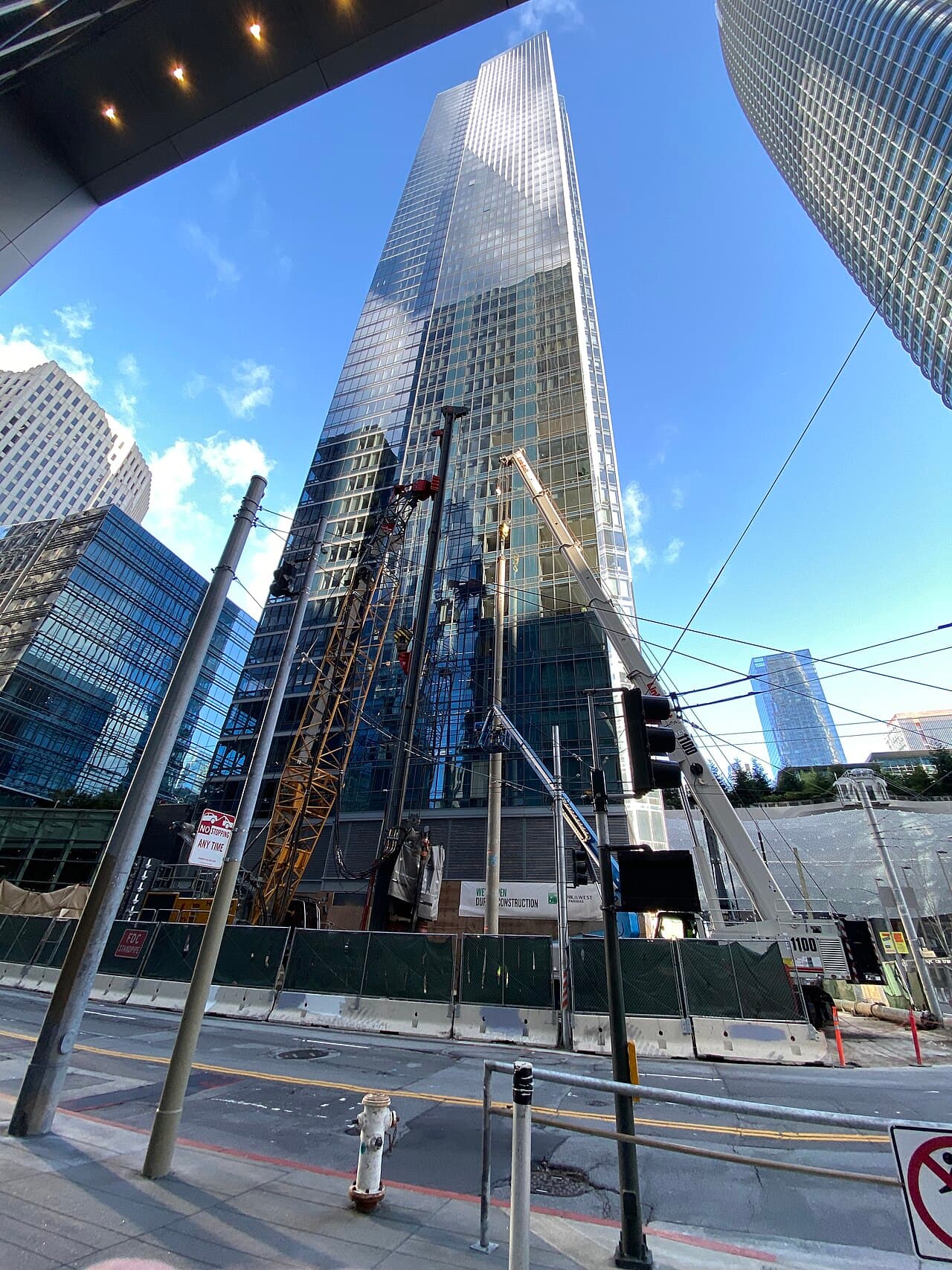 Workers and equipment installing a new foundation pile section next to the base of the Millennium Tower in San Francisco.
