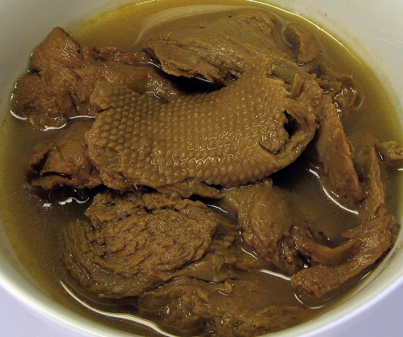A dish of wheat gluten prepared as a vegetarian mock duck, sliced and arranged on a plate.