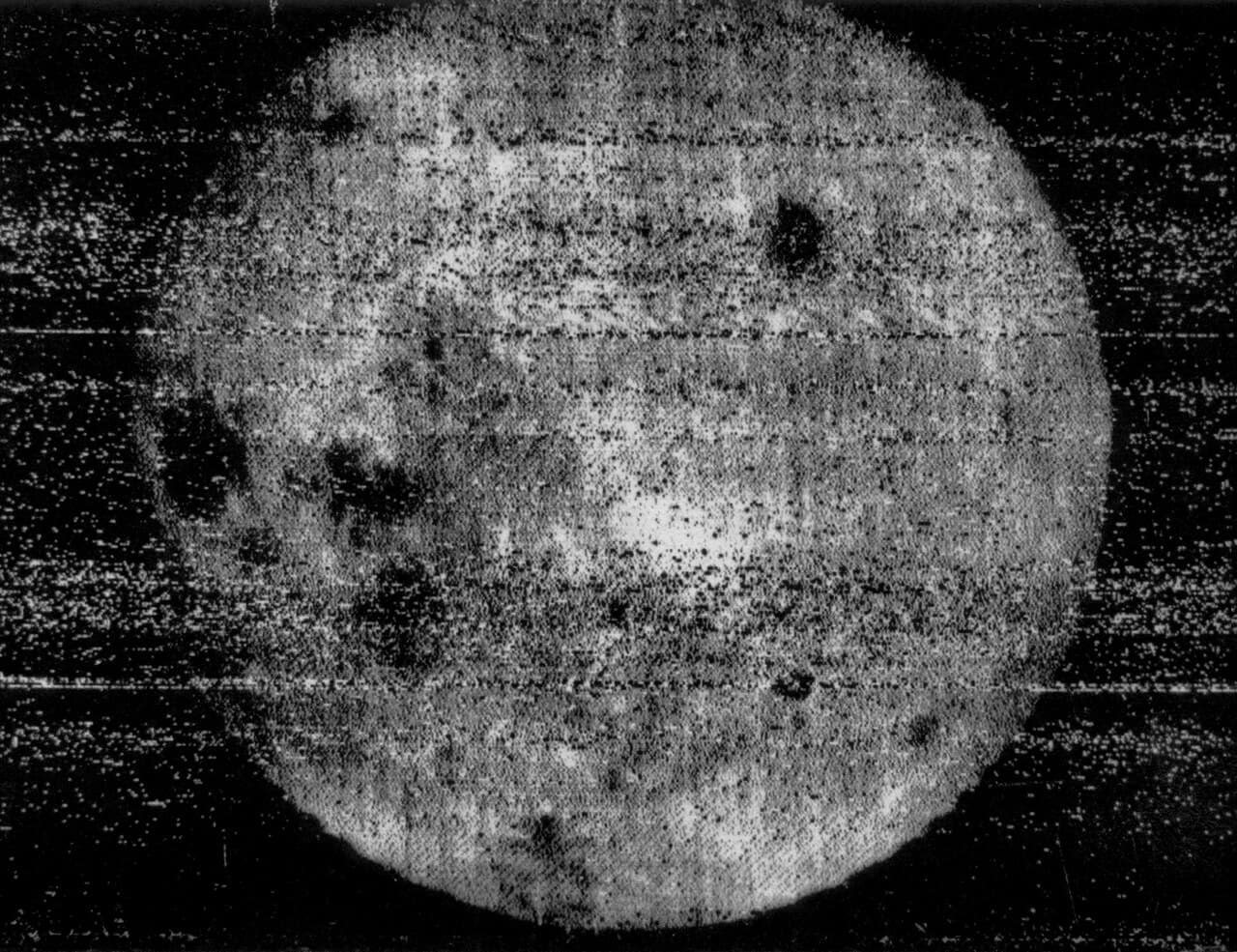 Grainy black-and-white photograph of the Moon's far side, the first ever taken, with a few dark patches.